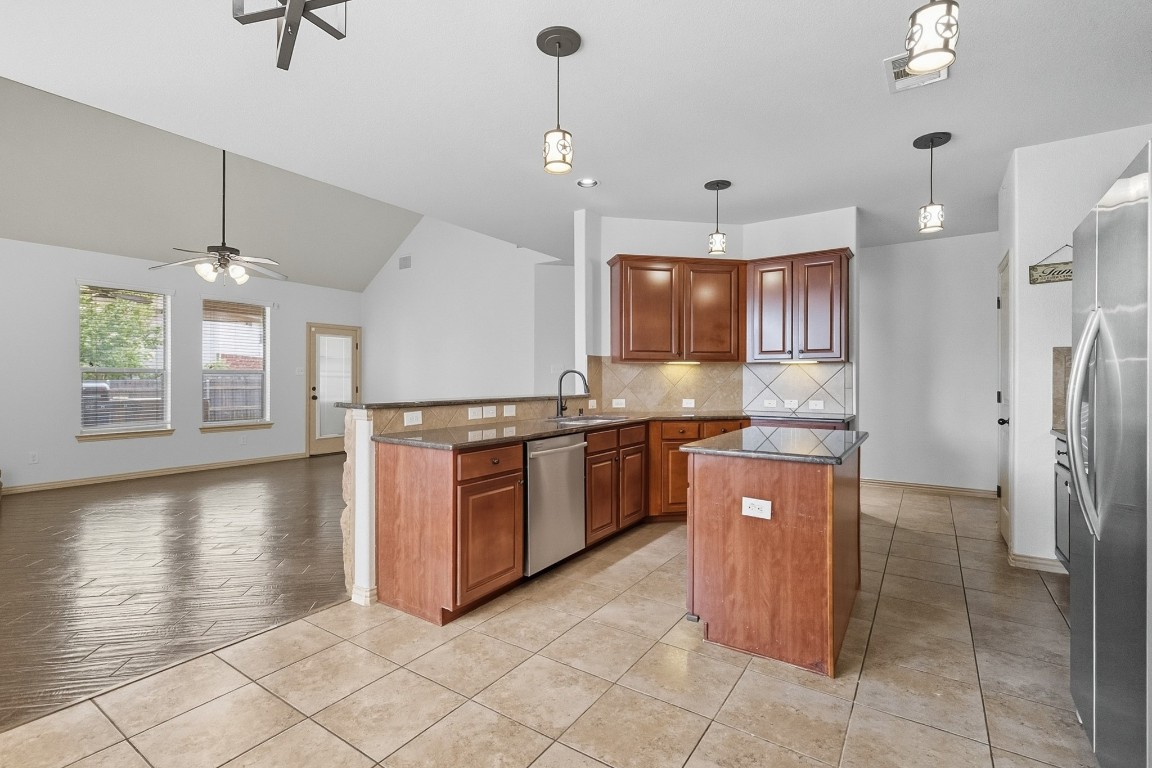 2409 Pauma Valley Way Pflugerville, TX 78660 - Photo 11 of 37 Kitchen featuring tasteful backsplash, light tile patterned floors, a peninsula, vaulted ceiling, and appliances with stainless steel finishes