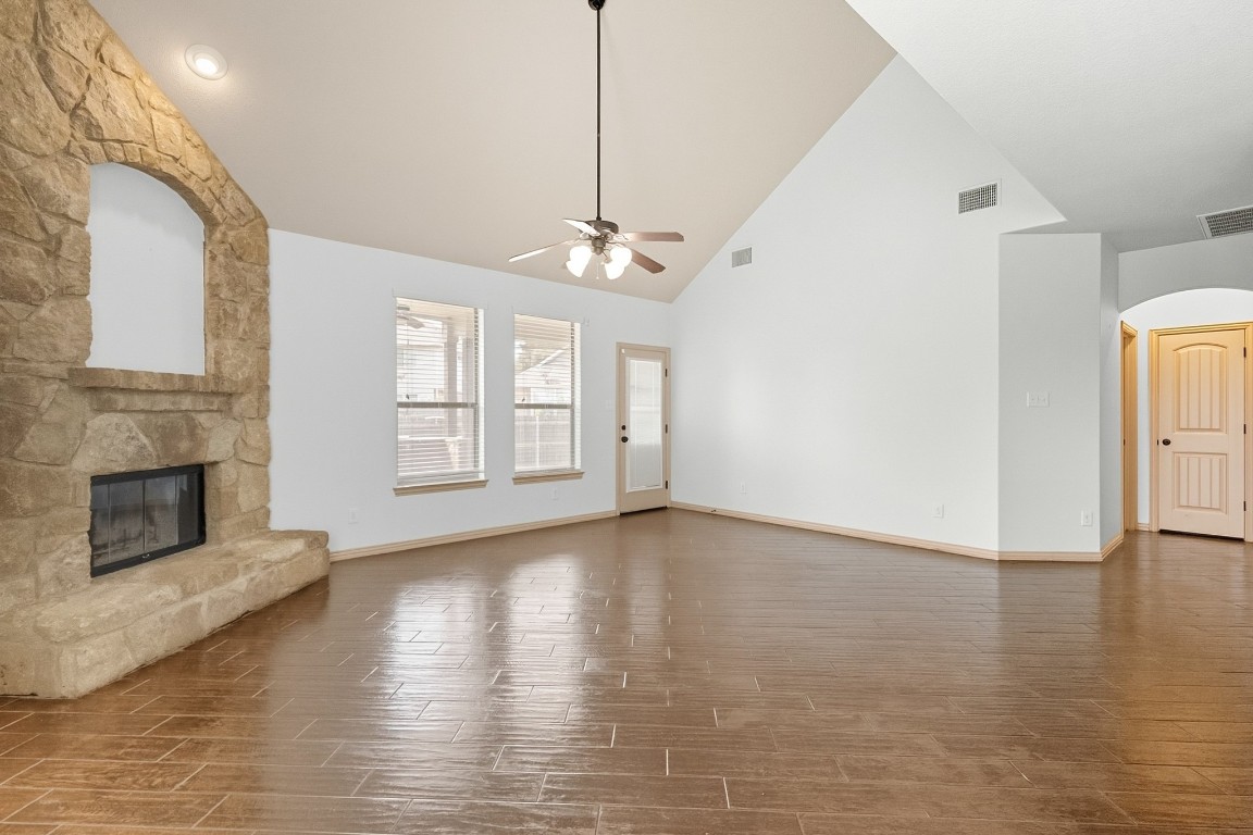 2409 Pauma Valley Way Pflugerville, TX 78660 - Photo 14 of 37 Unfurnished living room with high vaulted ceiling, a stone fireplace, wood finish floors, and ceiling fan