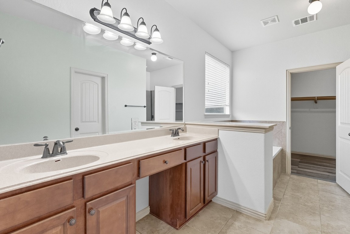 2409 Pauma Valley Way Pflugerville, TX 78660 - Photo 19 of 37 Bathroom featuring double vanity, a walk in closet, a bath, and light tile patterned floors