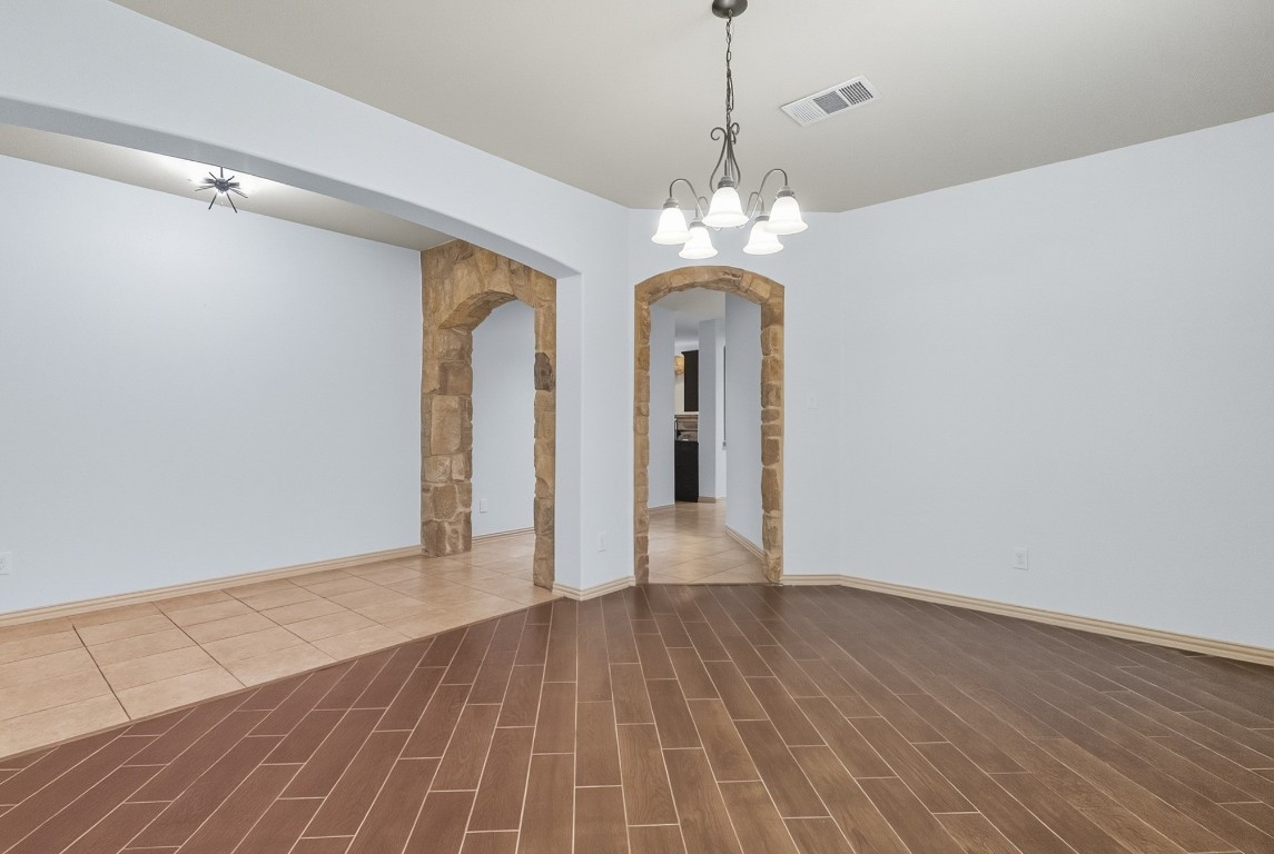 2409 Pauma Valley Way Pflugerville, TX 78660 - Photo 6 of 37 Spare room featuring a chandelier, arched walkways, and wood finished floors