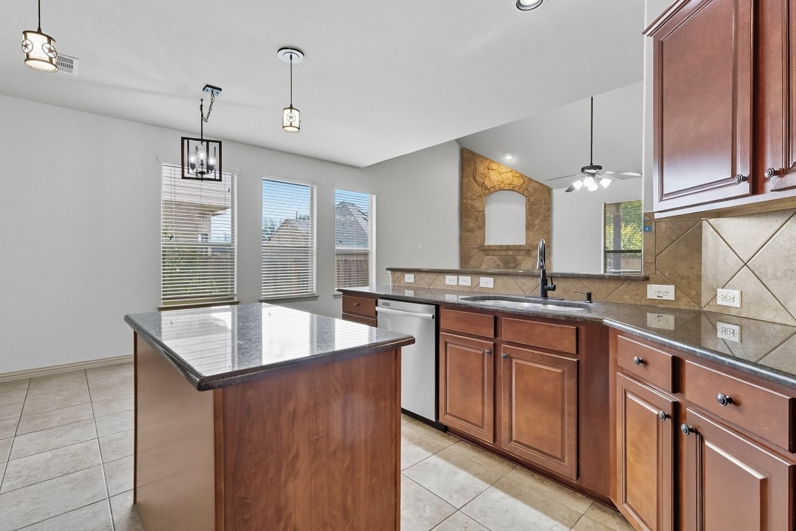 2409 Pauma Valley Way Pflugerville, TX 78660 - Photo 9 of 37 Kitchen with backsplash, hanging light fixtures, dark stone counters, light tile patterned floors, and recessed lighting
