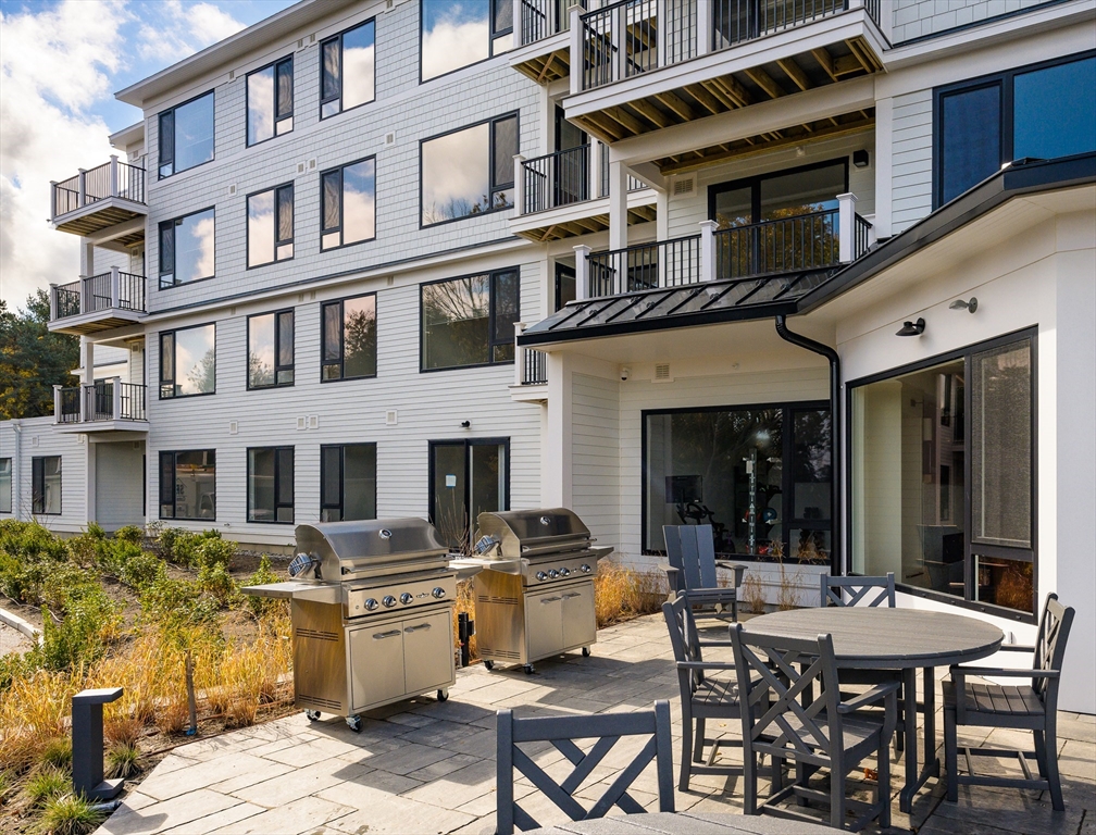 130 Chief Justice Cushing Highway, Unit 213 Scituate, MA 02066 - Photo 27 of 40 a view of a building with a table and chairs in patio
