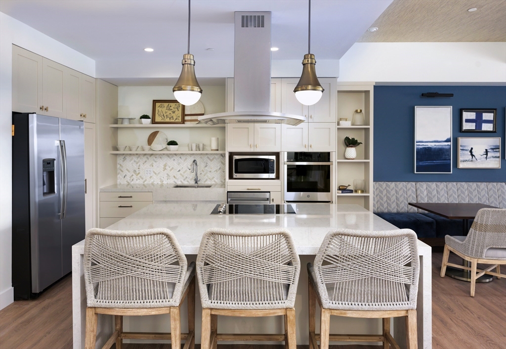 130 Chief Justice Cushing Highway, Unit 213 Scituate, MA 02066 - Photo 5 of 40 a kitchen with stainless steel appliances granite countertop a kitchen island hardwood floor and a view of living room
