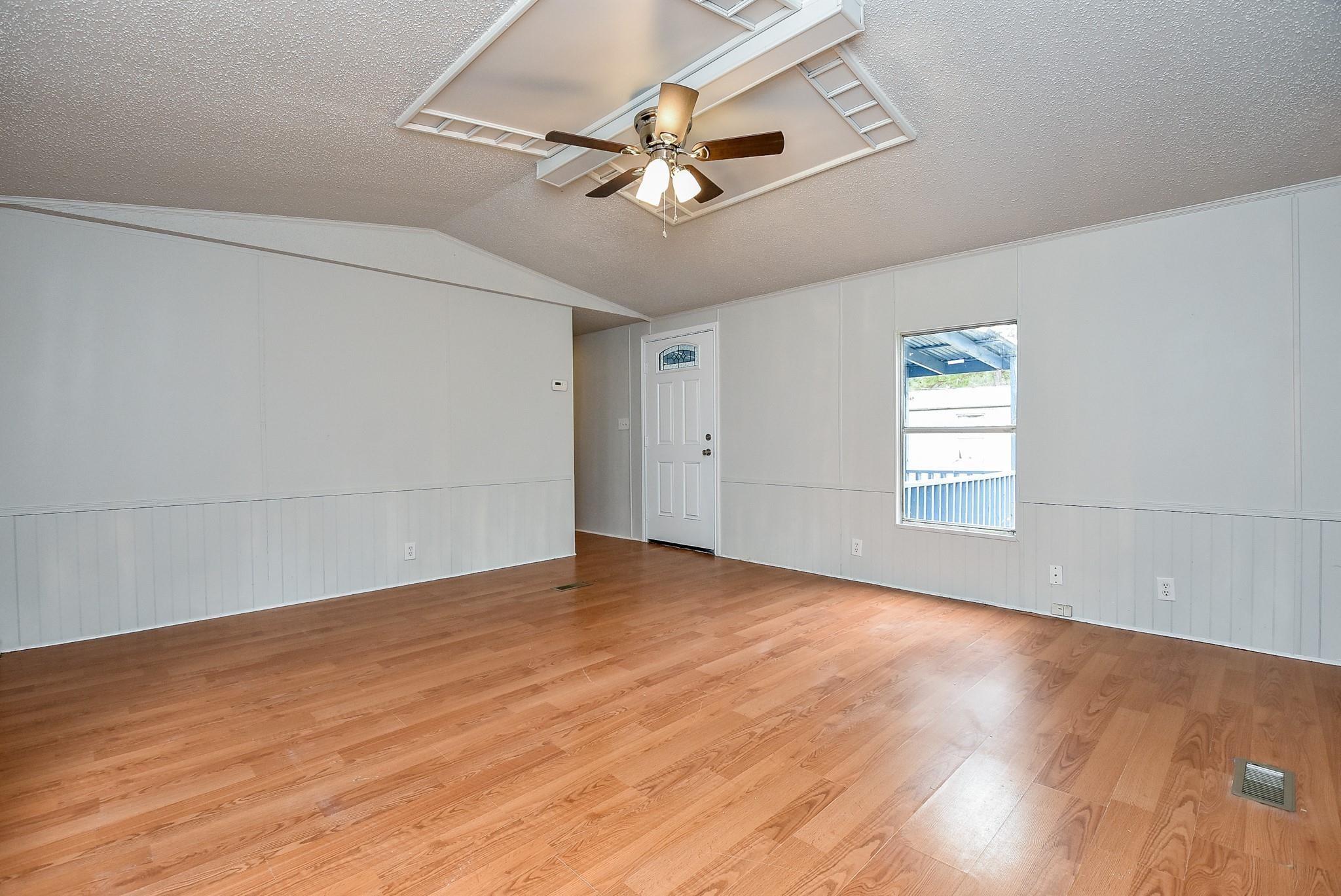 12842 Roy Harris Loop Conroe, TX 77306 - Photo 17 of 36 an empty room with wooden floor chandelier fan and windows
