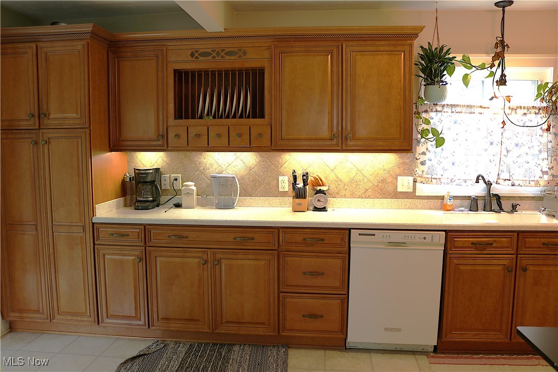 8233 Midland Road Mentor, OH 44060 - Photo 6 of 18 Kitchen with white dishwasher, brown cabinetry, light countertops, decorative backsplash, and a sink