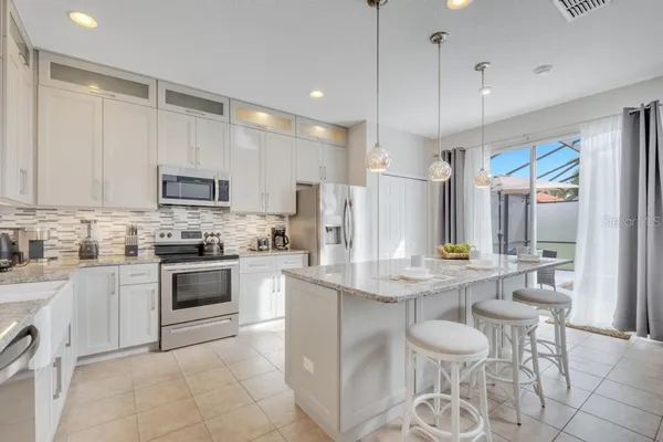a kitchen with stainless steel appliances kitchen island granite countertop a table chairs and a refrigerator