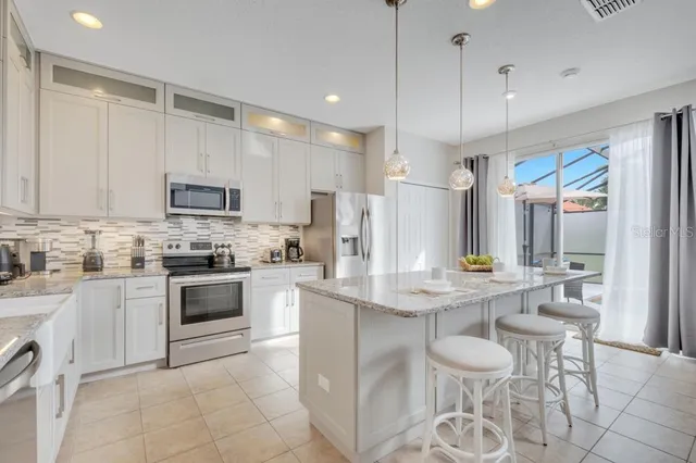 a kitchen with stainless steel appliances kitchen island granite countertop a table chairs and a refrigerator