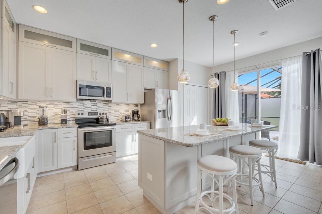 162 Cordova Avenue Davenport, FL 33897 - Photo 17 of 80 a kitchen with stainless steel appliances granite countertop a stove top oven a sink dishwasher a refrigerator and a dining table with white cabinets