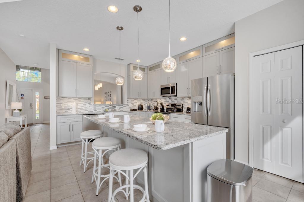 162 Cordova Avenue Davenport, FL 33897 - Photo 23 of 80 a kitchen with stainless steel appliances kitchen island granite countertop a table chairs and a refrigerator