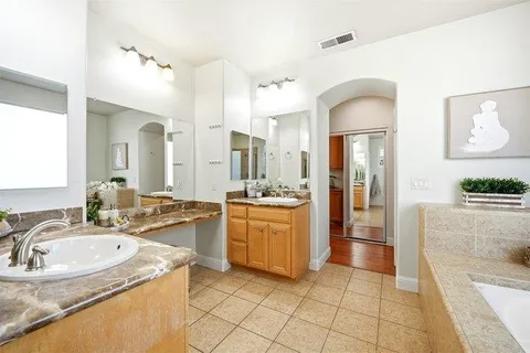 a bathroom with a granite countertop sink mirror and a bathtub