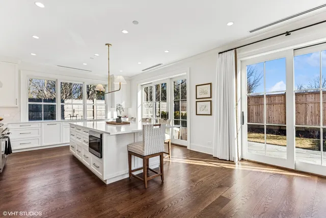 a large white kitchen with granite countertop a stove top oven a sink a dining table and chairs