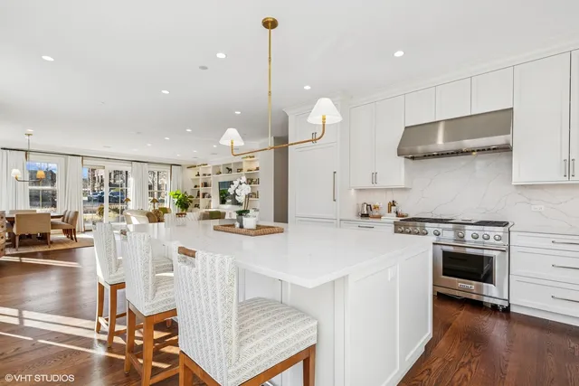 a kitchen with stainless steel appliances granite countertop a stove a sink a oven and a dining table with wooden floor