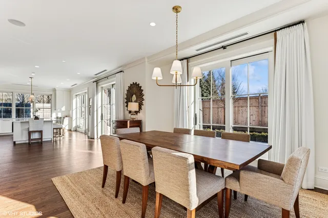 a dining room with wooden floor a chandelier a wooden table and chairs
