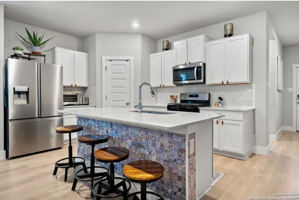 a kitchen with stainless steel appliances kitchen island granite countertop a refrigerator a stove a sink dishwasher and white cabinets with wooden floor