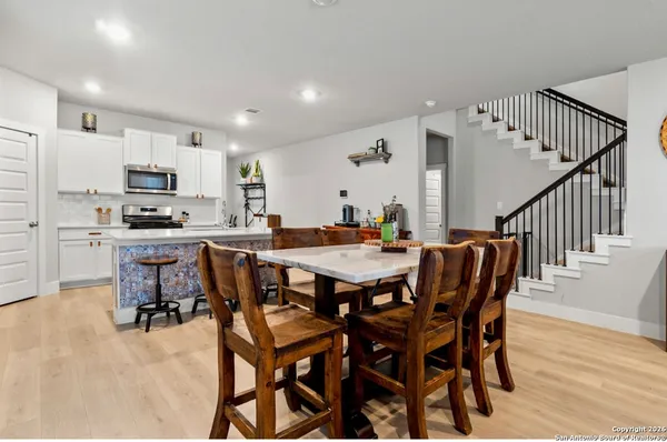 a dining area with stainless steel appliances kitchen island granite countertop a dining table chairs and a refrigerator