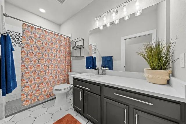 a bedroom with a bed a dresser and a chandelier