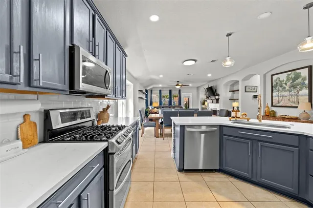 a kitchen with kitchen island granite countertop wooden cabinets a refrigerator oven a sink with island and chairs