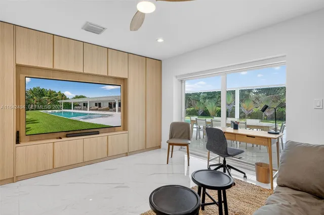 a living room with kitchen island furniture a flat screen tv and a large window