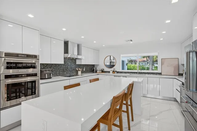 a white kitchen with wooden floor and stainless steel appliances