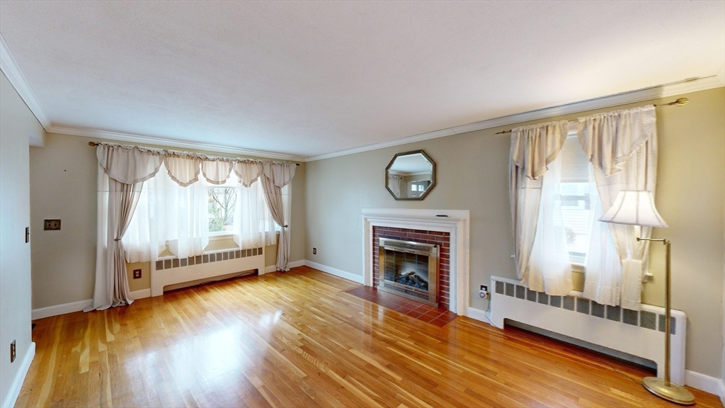 10 Wayland Road Wakefield, MA 01880 - Photo 8 of 28 a view of a livingroom with wooden floor a fireplace and a window