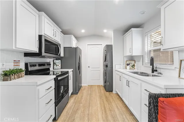 a kitchen with stainless steel appliances granite countertop a refrigerator a stove top oven a sink and dishwasher with wooden floor