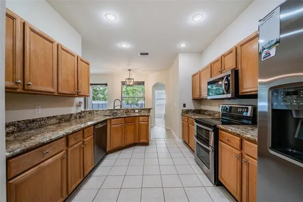 a large kitchen with stainless steel appliances granite countertop a stove top oven a sink dishwasher a dining table and chairs with wooden floor