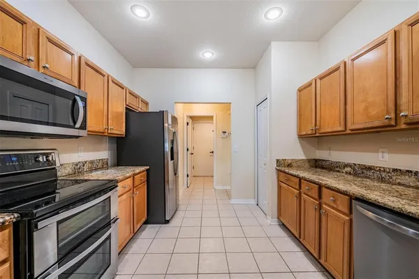 a kitchen with stainless steel appliances granite countertop a stove top oven a refrigerator a sink and dishwasher with wooden cabinets