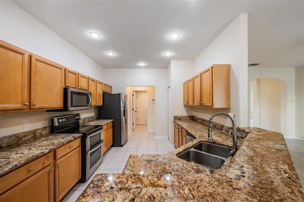 a kitchen with kitchen island granite countertop a sink stove and refrigerator