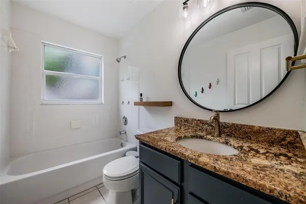 a bathroom with a granite countertop sink a toilet and a mirror