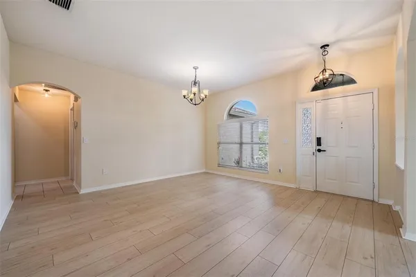 an empty room with wooden floor and chandelier
