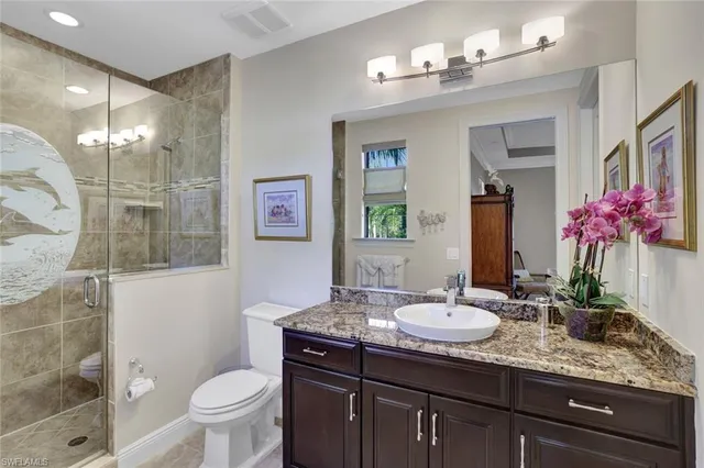 a bathroom with a granite countertop sink a toilet a mirror a vanity and shower