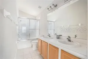 a bathroom with a double vanity sink toilet mirror and shower