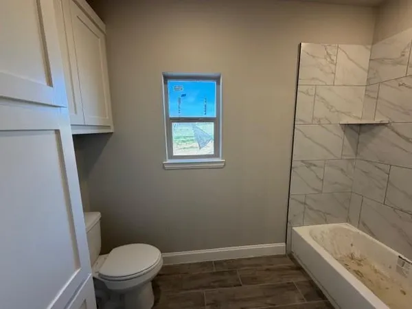 a bathroom with a granite countertop toilet and a bathtub