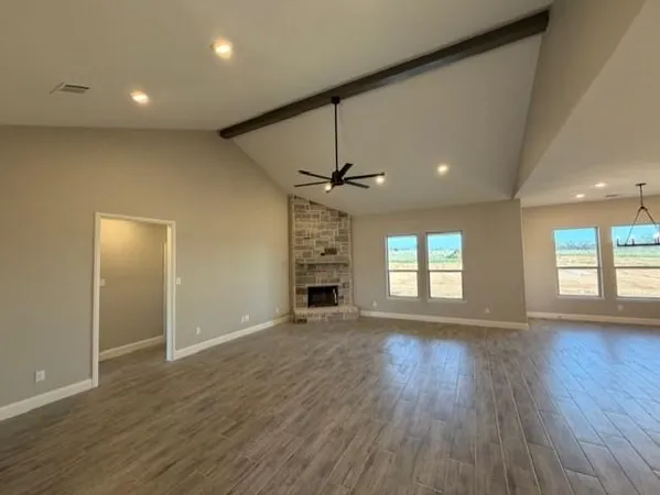 an empty room with wooden floor fireplace and windows