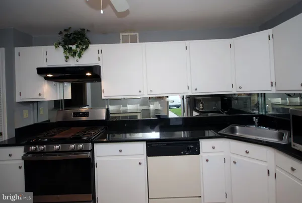 a kitchen with granite countertop white cabinets and black stainless steel appliances