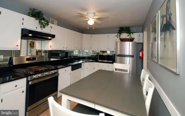 a kitchen with stainless steel appliances a stove a refrigerator a sink a stove and white cabinets