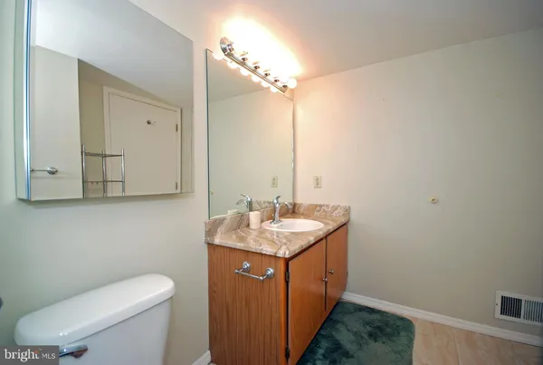 a bathroom with a granite countertop sink a toilet and mirror