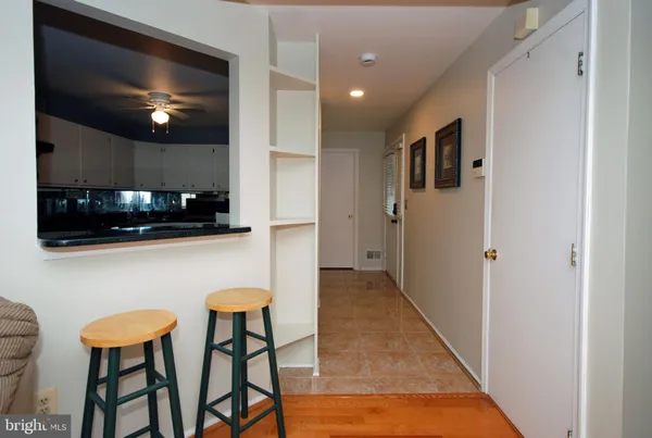 a kitchen with stainless steel appliances kitchen island granite countertop a refrigerator a stove a microwave oven with white cabinets and chairs