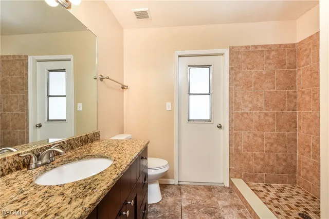 an empty room with ceiling fan and windows