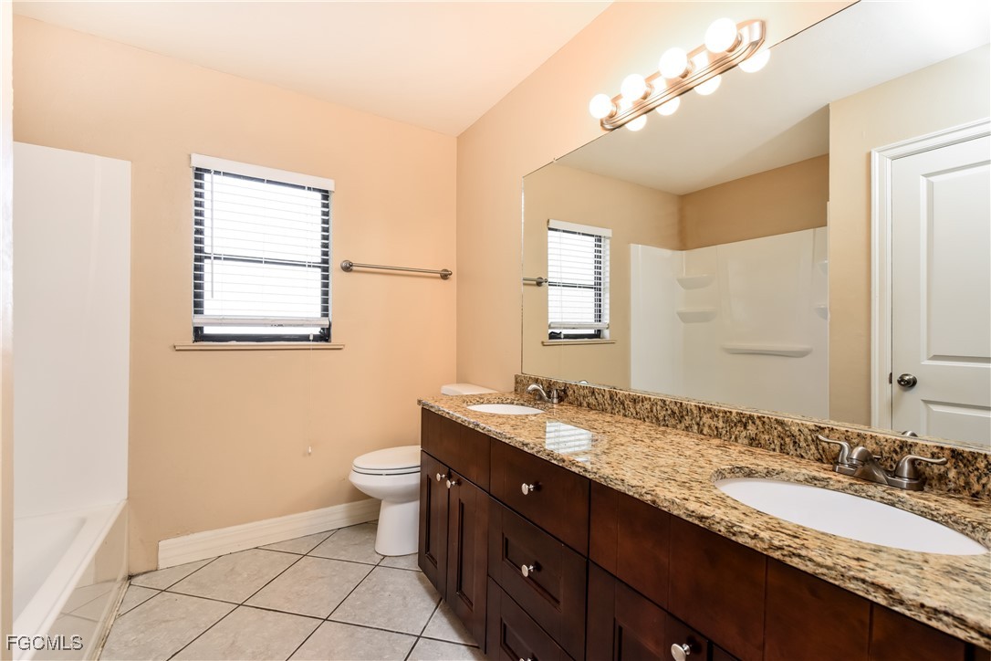 17365 Castile Road Fort Myers, FL 33967 - Photo 14 of 16 a bathroom with a granite countertop double vanity sink a mirror and a toilet