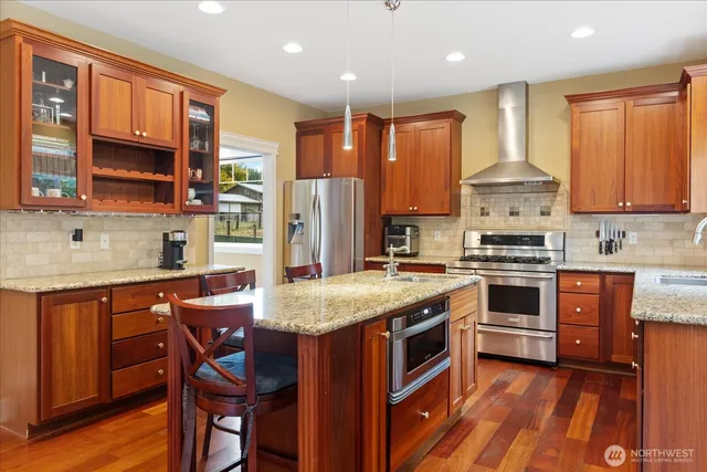 a kitchen with stainless steel appliances granite countertop a stove top oven a sink refrigerator and cabinets