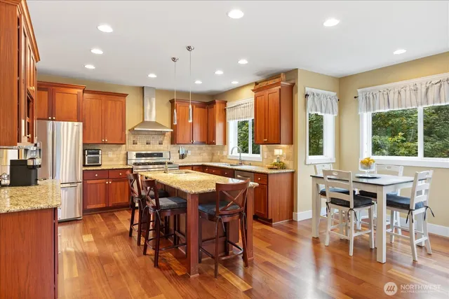 a kitchen with stainless steel appliances granite countertop a table chairs and a refrigerator