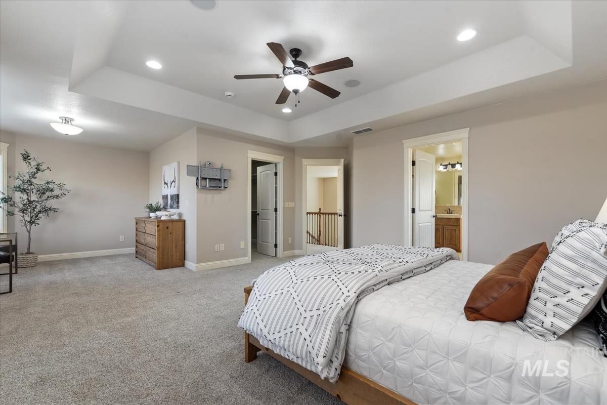 1082 East Azan Street Meridian, ID 83646 - Photo 23 of 47 Bedroom with a tray ceiling, carpet floors, ceiling fan, ensuite bathroom, and recessed lighting