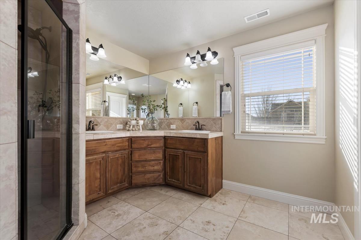 1082 East Azan Street Meridian, ID 83646 - Photo 27 of 47 Full bath with a stall shower, double vanity, light tile patterned floors, and tasteful backsplash