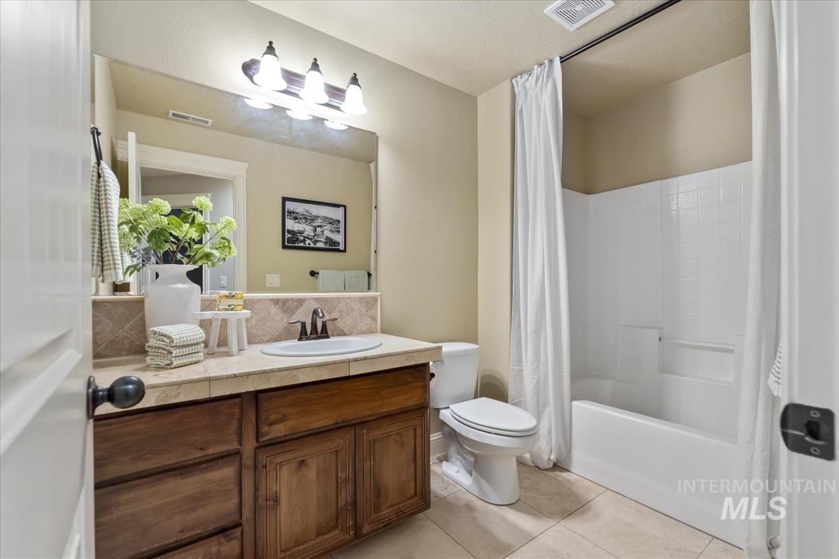 1082 East Azan Street Meridian, ID 83646 - Photo 34 of 47 Full bath with tasteful backsplash, vanity, shower / bathtub combination with curtain, and light tile patterned floors