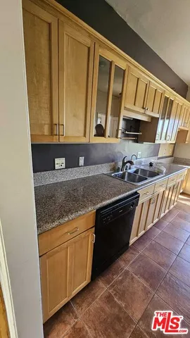 a view of a kitchen with a sink wooden cabinets and window