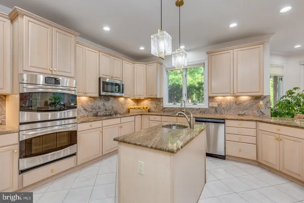 a kitchen with kitchen island granite countertop a sink stainless steel appliances and cabinets