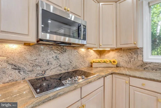 a kitchen with stainless steel appliances granite countertop a sink a stove a refrigerator and island with wooden floor