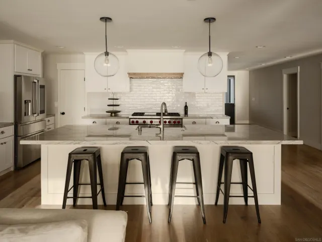 a white kitchen with stainless steel appliances granite countertop a stove a sink a refrigerator and island wooden floor