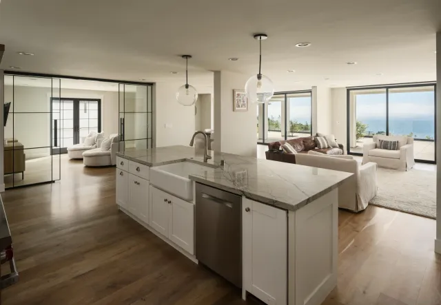 a large living room with stainless steel appliances kitchen island granite countertop wooden floor and a large window